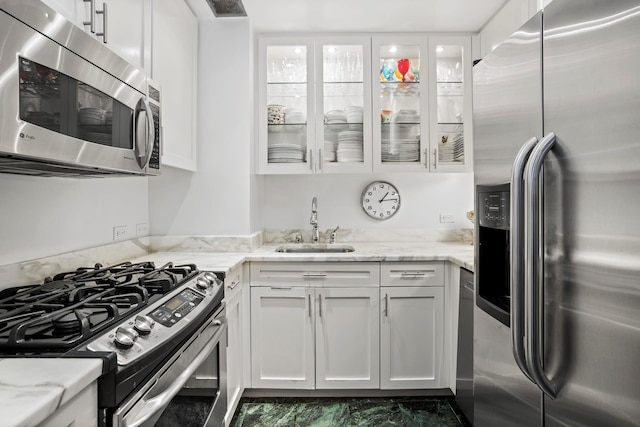 721 5th Ave Unit 33G, New York City, NY 10022 - kitchen with appliances with stainless steel finishes, white cabinets, glass insert cabinets, and light stone countertops