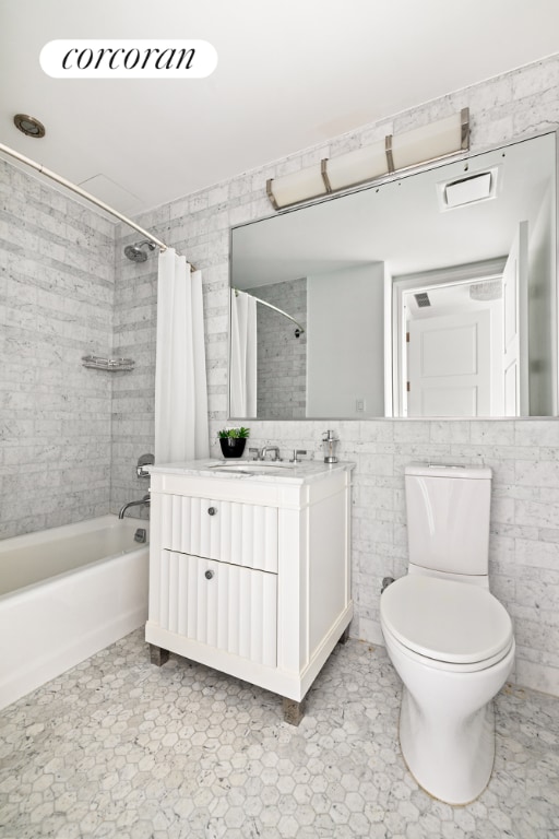 full bathroom with shower / tub combo with curtain, vanity, toilet, and tile walls