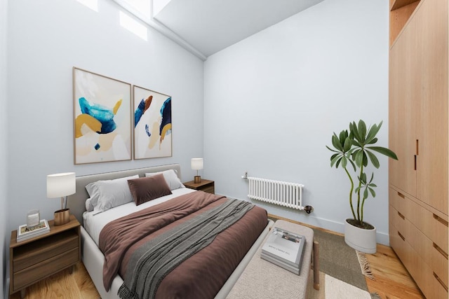 bedroom with light wood-style floors, baseboards, and radiator heating unit