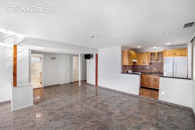 kitchen with white appliances, a sink, visible vents, backsplash, and glass insert cabinets