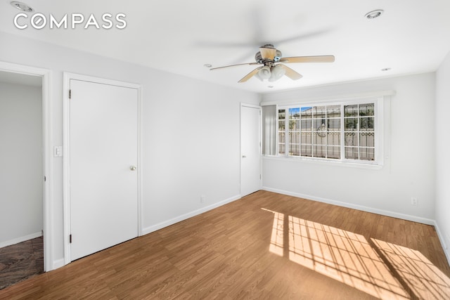 empty room featuring a ceiling fan, baseboards, and wood finished floors