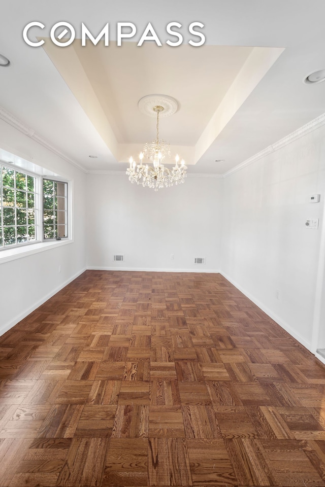 spare room featuring baseboards, visible vents, a raised ceiling, and a chandelier