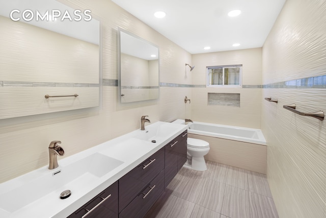 bathroom with toilet,  shower combination, a sink, and tile walls