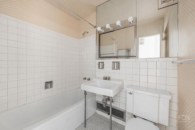 bathroom featuring tile walls, toilet, tiled shower / bath, and tile patterned flooring