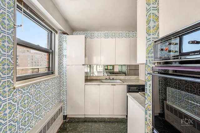 kitchen with white cabinets, baseboard heating, and sink