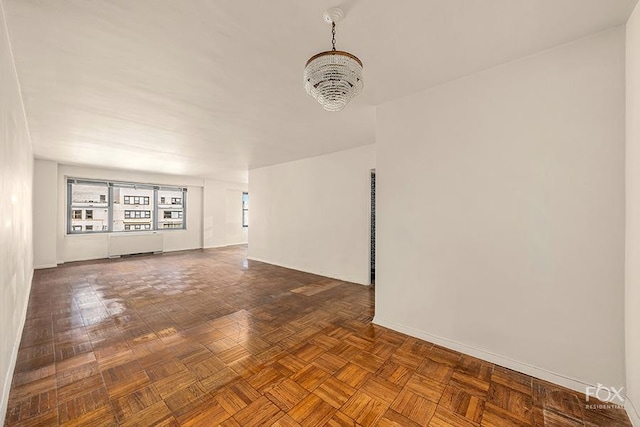 empty room featuring an inviting chandelier, parquet flooring, and radiator heating unit