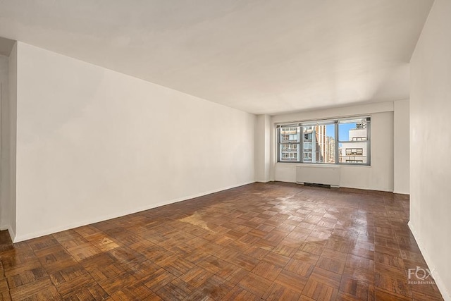 unfurnished room with dark parquet flooring and radiator heating unit