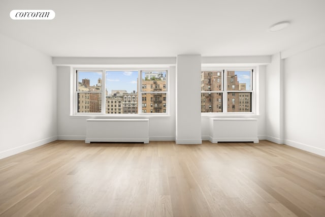 unfurnished room featuring baseboards, visible vents, a city view, and wood finished floors