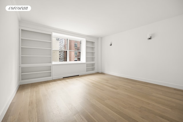 55 E 87th St Unit 14E, New York City, NY 10128 - empty room with built in shelves, light wood finished floors, and baseboards