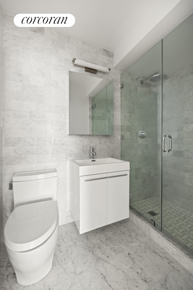 55 E 87th St Unit 14E, New York City, NY 10128 - full bathroom featuring vanity, a stall shower, toilet, marble finish flooring, and tile walls