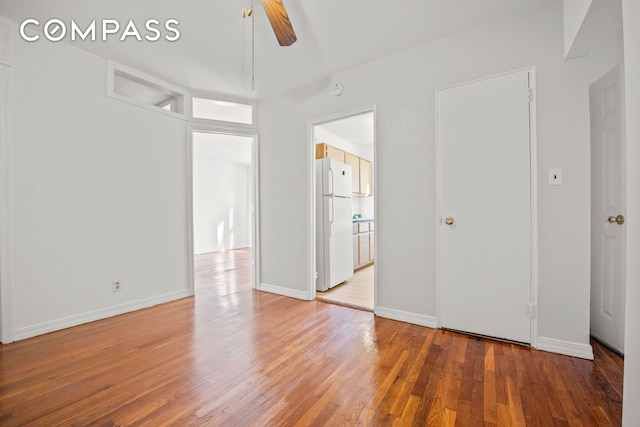 unfurnished bedroom with baseboards, a ceiling fan, freestanding refrigerator, and light wood-style floors