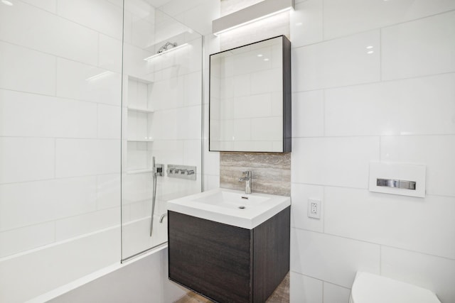 full bath with  shower combination, vanity, toilet, and tile walls