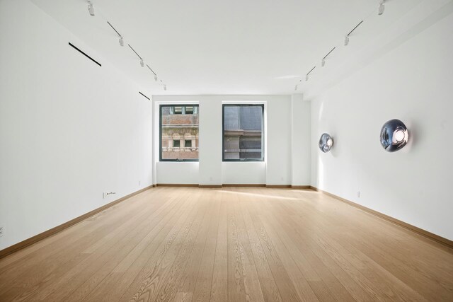 unfurnished room featuring light wood-type flooring, baseboards, and track lighting