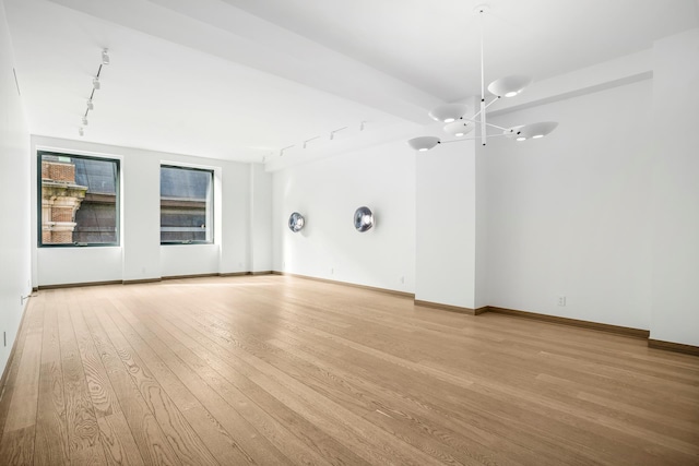 unfurnished room with rail lighting, light wood-style flooring, and baseboards