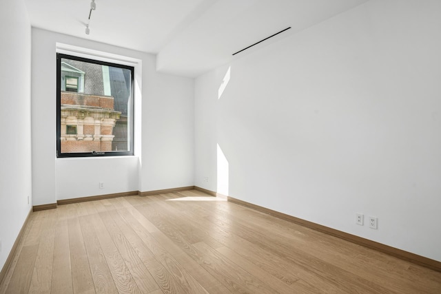 unfurnished room featuring light wood-type flooring, baseboards, and track lighting