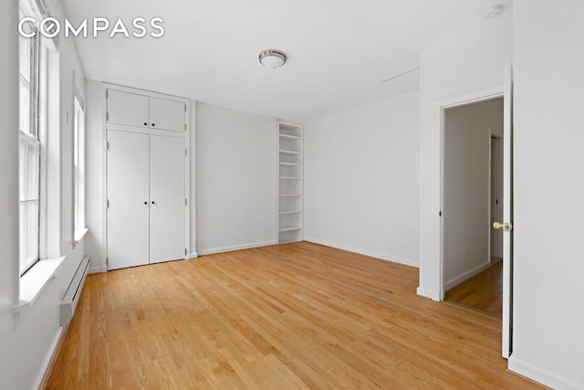 10 Bedford St, New York City, NY 10014 - unfurnished bedroom featuring light wood-type flooring, a baseboard radiator, and a closet