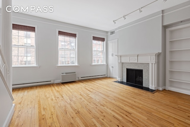 10 Bedford St, New York City, NY 10014 - unfurnished living room featuring a baseboard radiator, hardwood / wood-style floors, built in features, and a fireplace with flush hearth