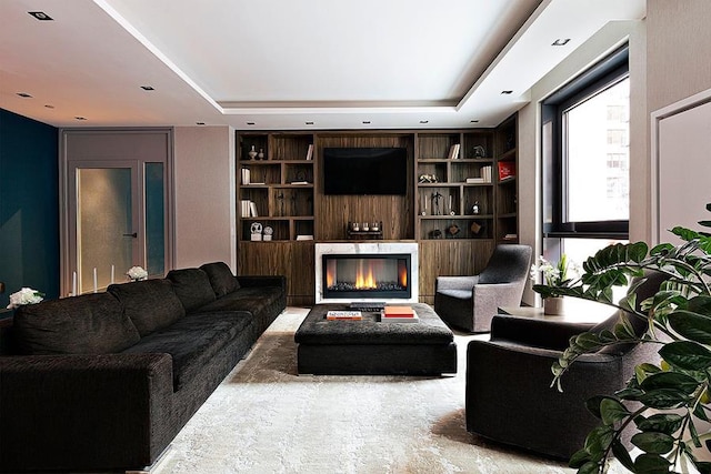 living room featuring a raised ceiling and built in shelves