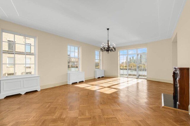 dining space featuring a healthy amount of sunlight, dark parquet flooring, and an inviting chandelier