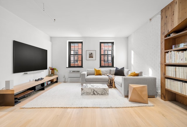 living area featuring brick wall and light wood-style flooring