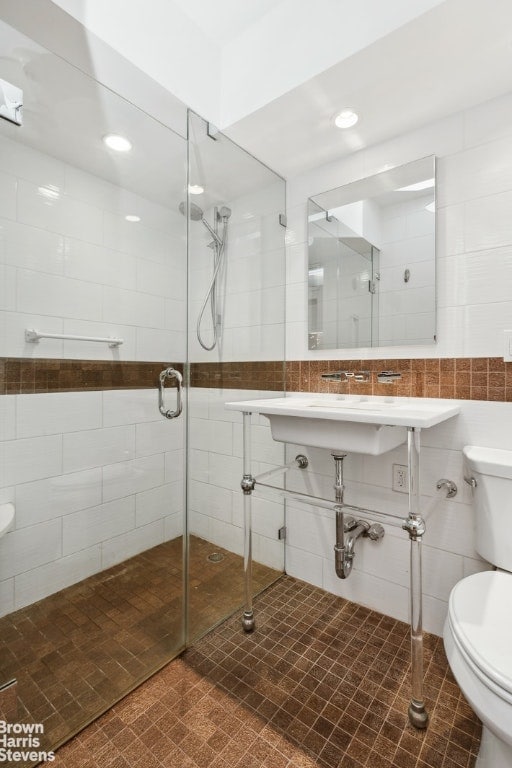 bathroom with toilet, tile patterned flooring, tile walls, and a shower with door