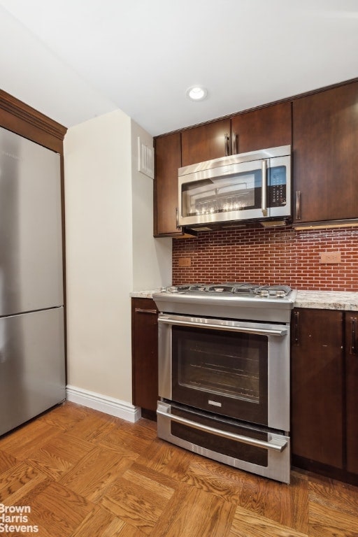 kitchen with appliances with stainless steel finishes, dark brown cabinets, and tasteful backsplash