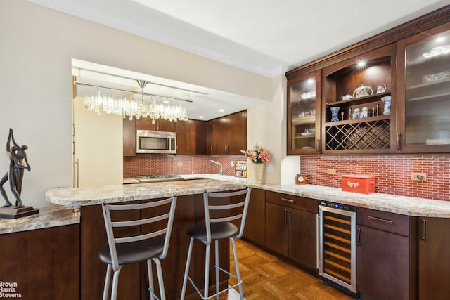 bar with wine cooler, backsplash, dark parquet flooring, pendant lighting, and dark brown cabinetry