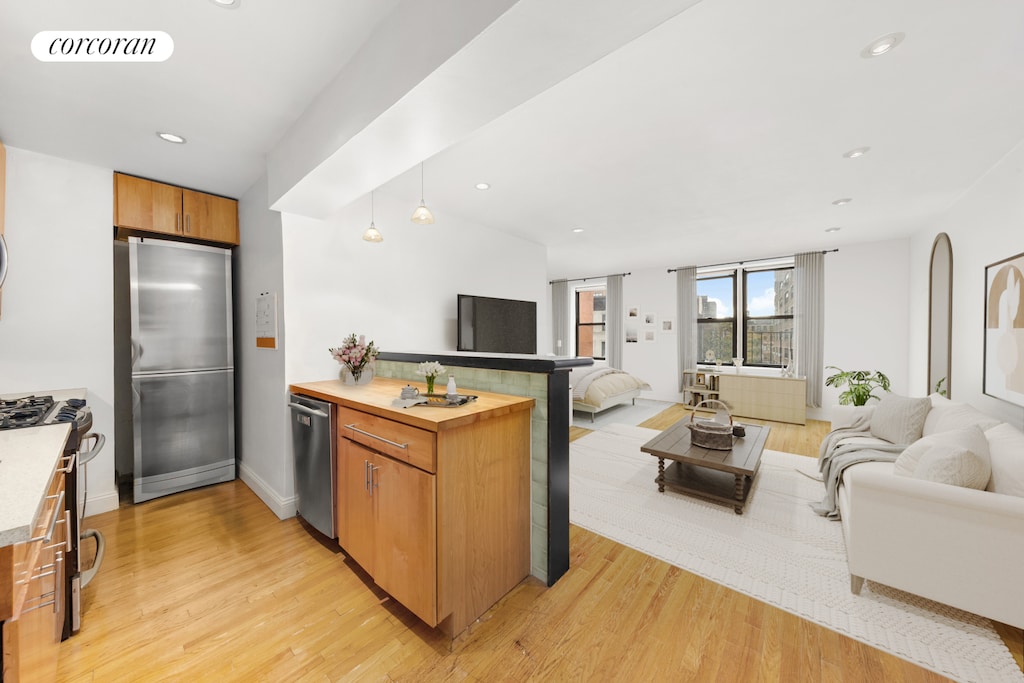kitchen featuring a peninsula, appliances with stainless steel finishes, light wood finished floors, and open floor plan
