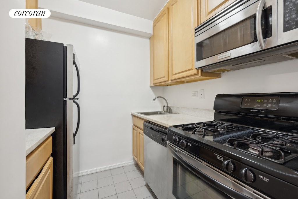 1725 York Ave Unit 14A, New York City, NY 10128 - kitchen with appliances with stainless steel finishes, light brown cabinetry, light countertops, light tile patterned floors, and a sink