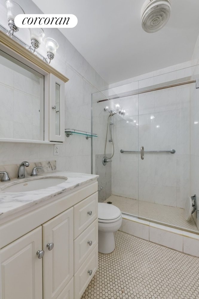 1725 York Ave Unit 14A, New York City, NY 10128 - bathroom featuring a stall shower, toilet, and vanity