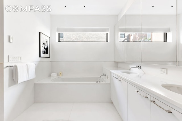 full bathroom with a sink, a bath, double vanity, and tile patterned flooring