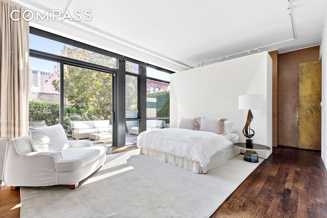 bedroom featuring a wall of windows, wood finished floors, and access to exterior