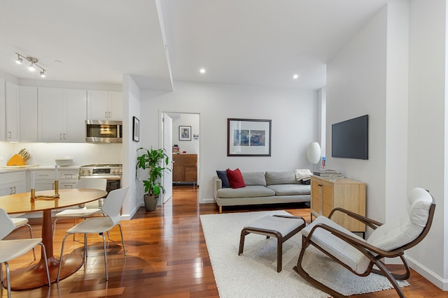 living area featuring baseboards, hardwood / wood-style floors, and recessed lighting