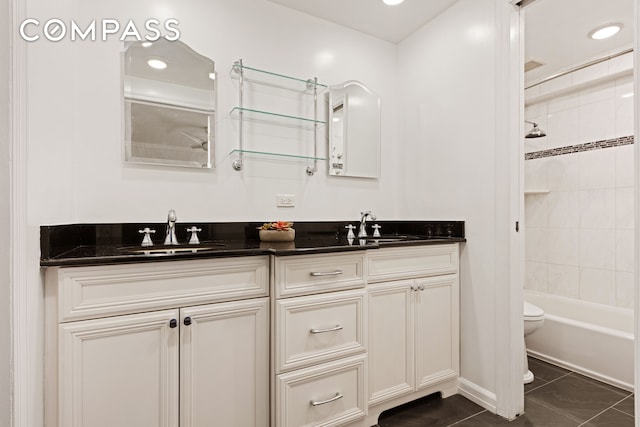 full bath with double vanity, a sink, toilet, and tile patterned floors