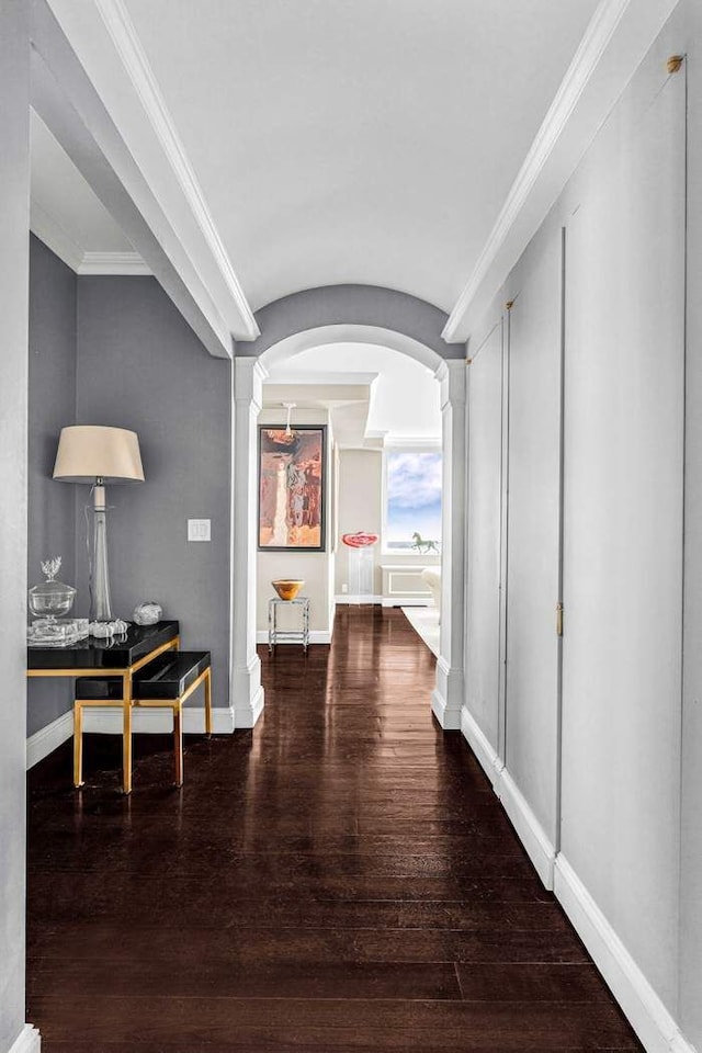 corridor with arched walkways, hardwood / wood-style floors, baseboards, and decorative columns