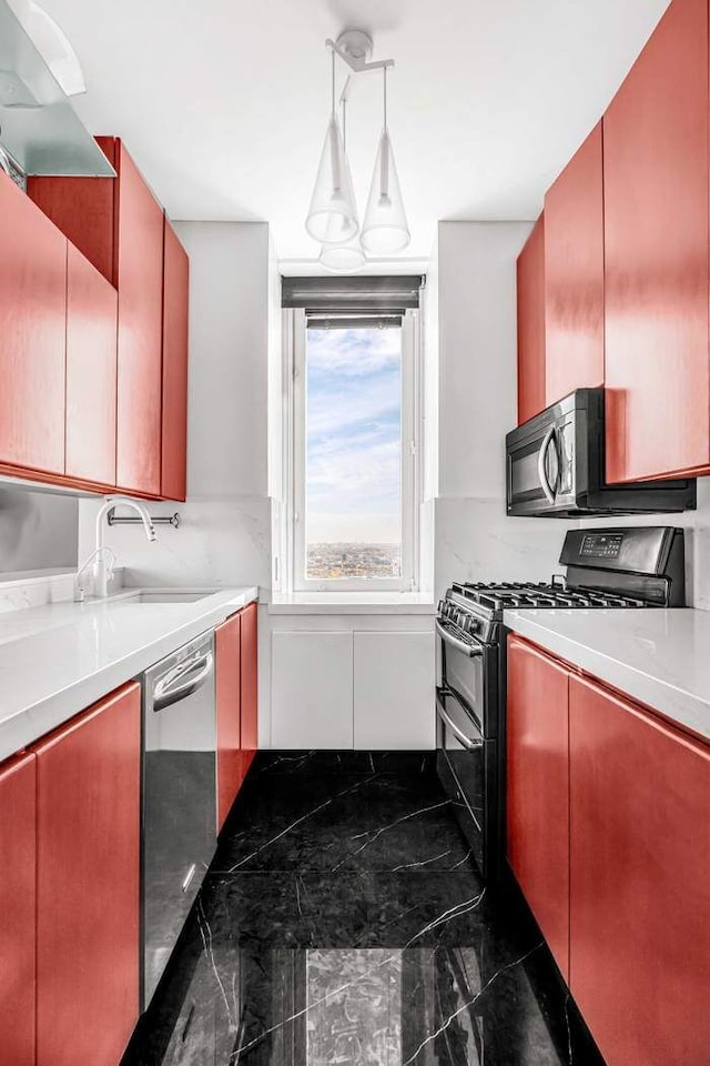 kitchen featuring marble finish floor, a sink, appliances with stainless steel finishes, light countertops, and hanging light fixtures