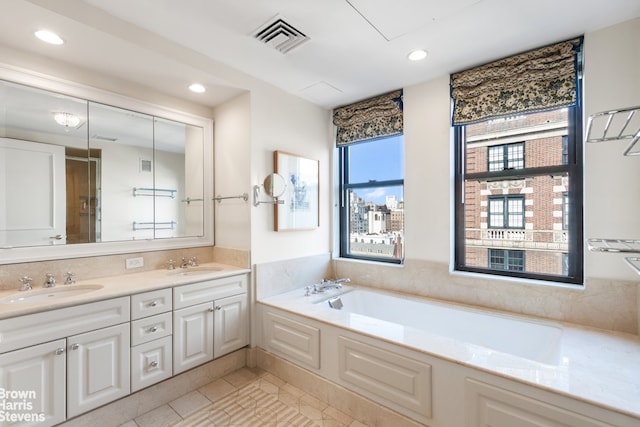 full bathroom with double vanity, a garden tub, visible vents, and a sink