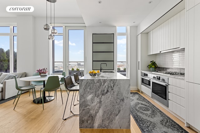 kitchen with a sink, visible vents, white cabinetry, light wood finished floors, and modern cabinets