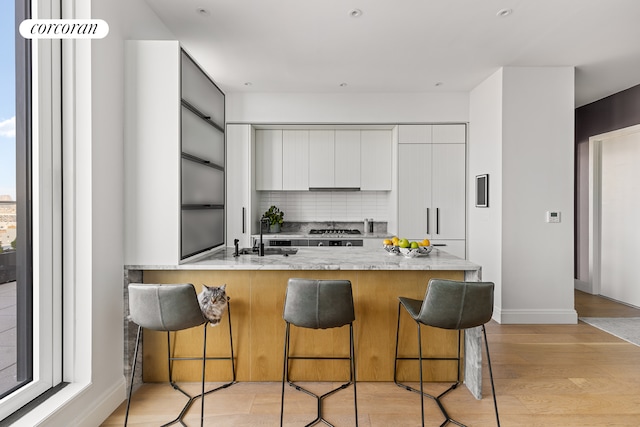 kitchen featuring a peninsula, a breakfast bar, modern cabinets, and a sink