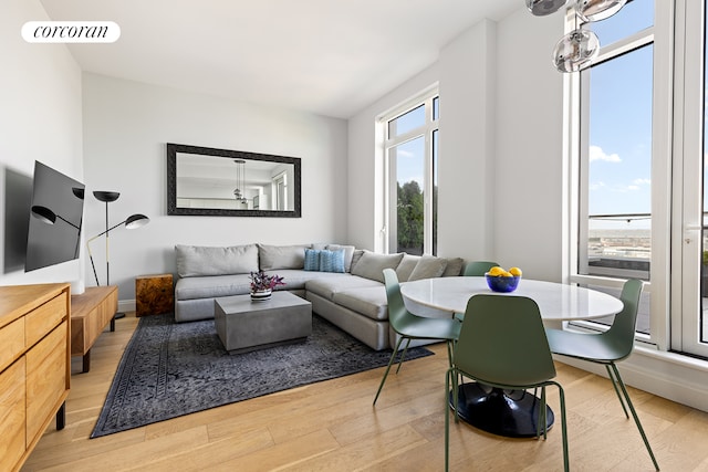 living area featuring light wood-style floors, baseboards, visible vents, and a notable chandelier