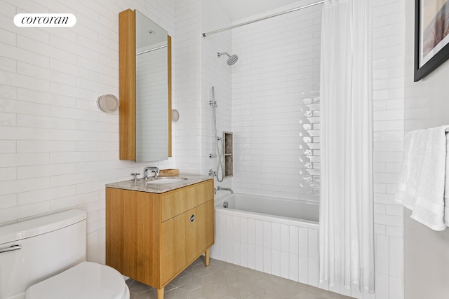 bathroom featuring tile walls, tiled shower / bath, toilet, vanity, and tile patterned floors