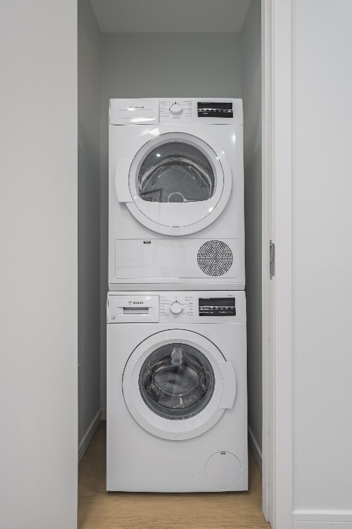 clothes washing area featuring stacked washer / drying machine and light wood-type flooring