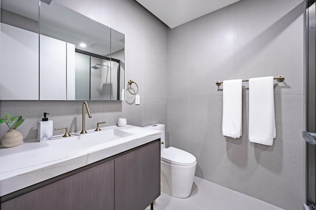 bathroom with toilet, tile walls, a shower with shower door, and vanity