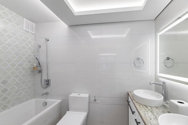 bathroom with vanity, tile walls, and tiled shower / bath