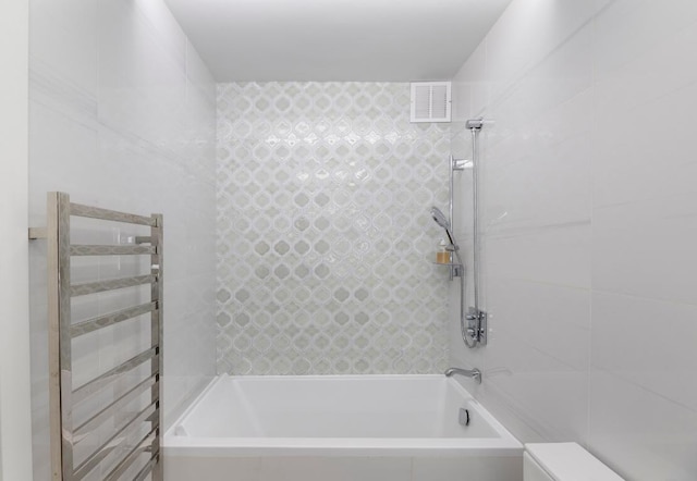 bathroom with radiator and tiled shower / bath