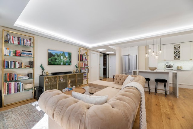 living room featuring a tray ceiling and light hardwood / wood-style floors