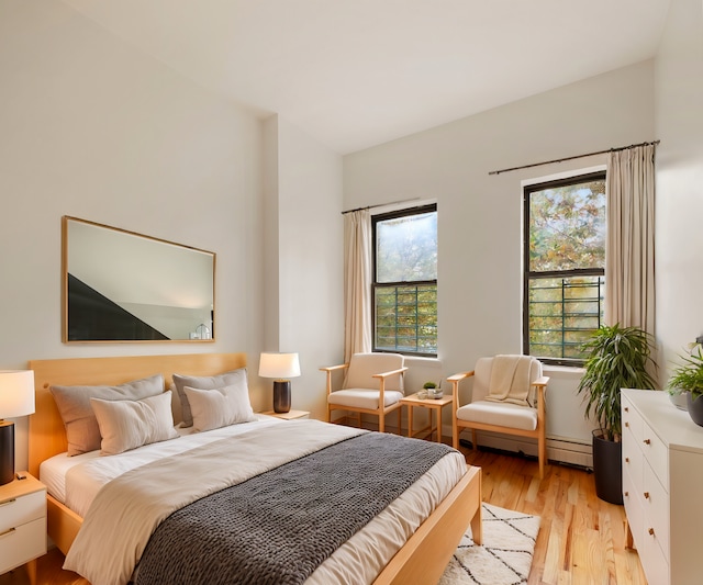 bedroom with light wood-style flooring and a baseboard radiator