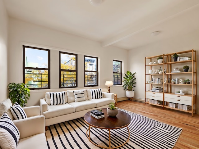 living room with a wealth of natural light, beamed ceiling, and light wood-type flooring