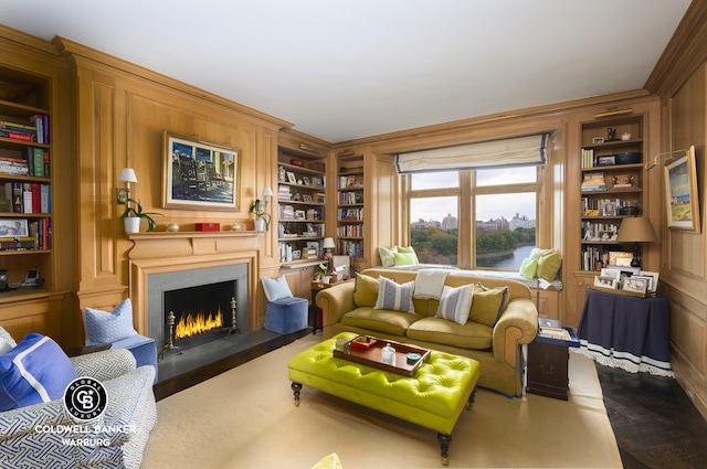 living area featuring built in features, a warm lit fireplace, and crown molding