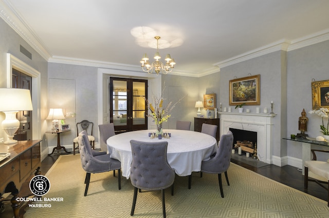 dining space with wood finished floors, a chandelier, a high end fireplace, ornamental molding, and french doors